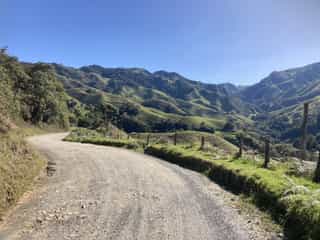 Onverharde weg kronkelt door de zonovergoten, groene bergen van Colombia's landschap.