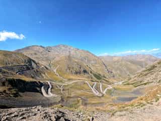 Winding mountain roads through a vast and dry Georgian landscape under a bright blue sky.