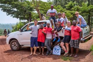 Het Veloglobe team op de foto met de crew in Rwanda op en rond een jeep.