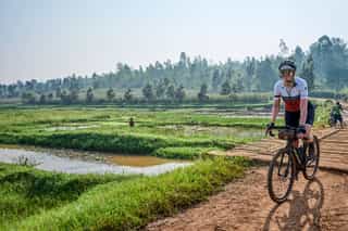 Veloglobe deelneemster tussen de groene velden aan het fietsen in Rwanda